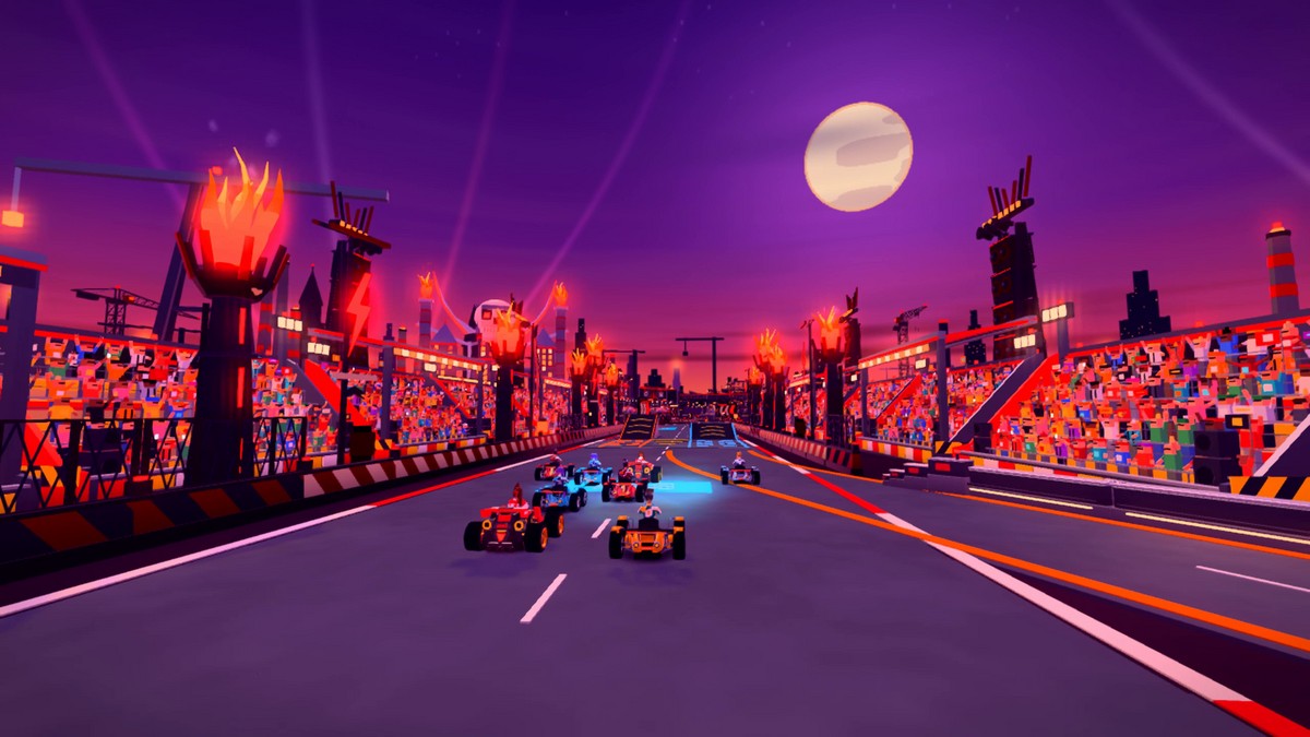 Karts racing through the Riot Arena between packed grandstands, flame towers and ramps beneath a purple skyline.